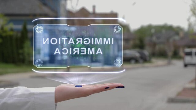 Female hand showing conceptual hologram with text Immigration America. Unrecognizable woman in white holds future holographic technology on the background of a street with private houses