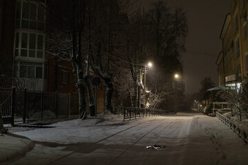 a night blizzard in the city, a quiet deserted park in the light of lanterns, a winter landscape of a quiet street