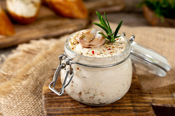 Chicken pate in a glass jar on the brown wooden kitchen table. Homemade chicken fillet pate with seasonings on a wooden background
