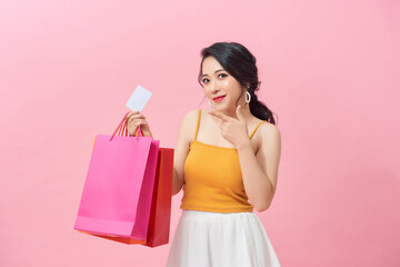 Portrait of a beautiful girl wearing dress and holding colorful shopping bags and showing credit...