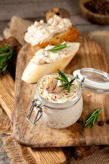 Chicken pate in a glass jar on the brown wooden kitchen table. Homemade chicken fillet pate with seasonings on a wooden background