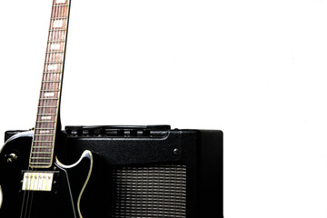 Black electric guitar with guitar amplifier on a white background