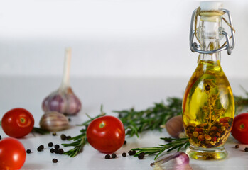 Fresh olives and oil in bottle with rosemary on white background with scattered cherry tomatoes end spicies, top view. Organic olive oil concept