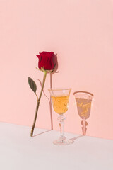 A love concept made with a glass of drink and a red rose on a pink background. Minimal composition