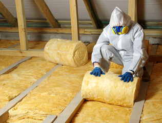 Construction worker installing glass wool