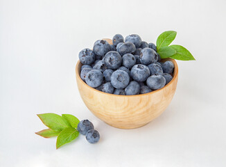 Fresh blueberries in a wooden bowl on a white background