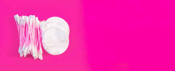 White cotton cotton pads and pink cotton swabs on a pink background. Copy space. © Olga