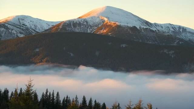 Time lapse landscape of Hoverla mountain, the highest peak in ukrainian Carpathian mountains surrounded with white fast moving foggy clouds at sunrise.