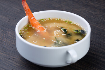 Miso soup with tofu, shrimp and seaweed in a white bowl