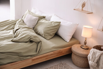 Comfortable bed with olive green linen in modern room interior - obrazy, fototapety, plakaty