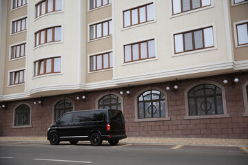 Fototapeta na wymiar Black delivery van parked on street near building