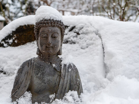 Buddha im Schnee in ein Winterlandschaft im Garten