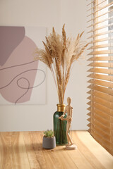 Dry plants on wooden table near window indoors. Interior design