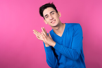 A young man gestures with his hands. Pink background. Consent and denial. Good and bad.