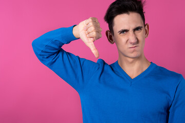 A young man gestures with his hands. Pink background. Consent and denial. Good and bad.