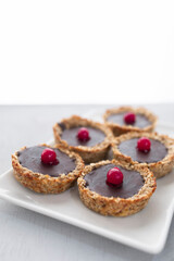 Homemade gluten-free tartlet with oats, banana and black chocolate and red cranberry