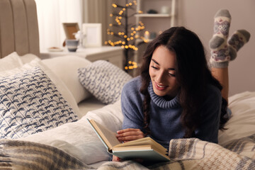 Young woman reading book at home. Winter atmosphere