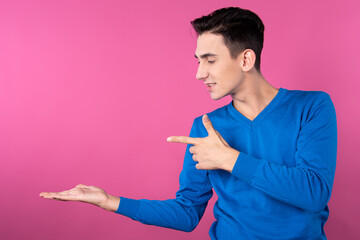 A young man gestures with his hands. Pink background. Consent and denial. Good and bad.
