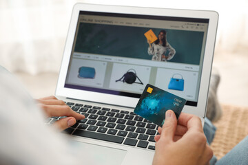 Woman with credit card using laptop for online shopping indoors, closeup