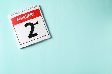 Top view of calendar with date February 2nd on light blue background, space for text. Groundhog day