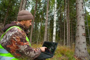 Forest engineer works in the forest with a computer. Digital technologies in forestry. Computer forest inventory.