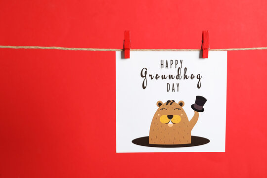 Happy Groundhog Day greeting card hanging on red background, space for text