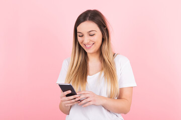 Naklejka premium a young blonde woman smiles happily looking at her cell phone