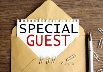 special guest, Text on white paper. on paper in an envelope on a wooden table.