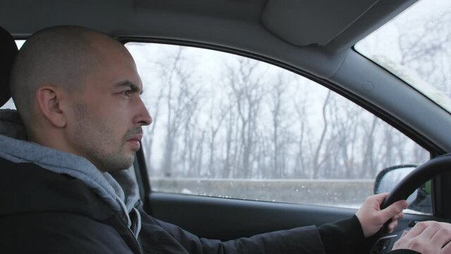 A tired man drives a car on the highway in winter and falls asleep.