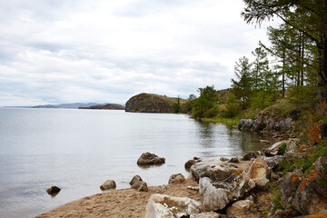 Lake Baikal on a cloudy summer day. Rocky shore of the lake, the clear, calm water.