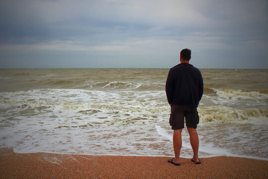A man stands on the seashore and looks into the distance. Selective focus. Background. Scenery.