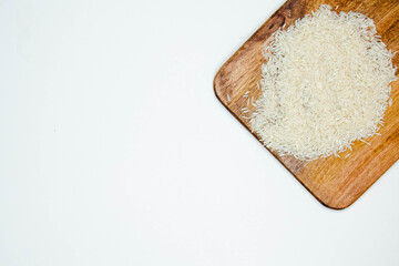 Long grain white rice, on black walnut chopping board isolated on white background. Copy space.