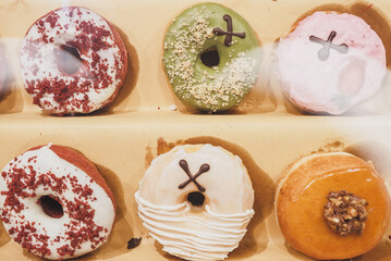Assorted tasty colorful donuts on display, close up view. Street food market