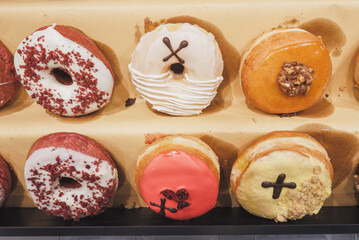 Assorted tasty colorful donuts on display, close up view. Street food market