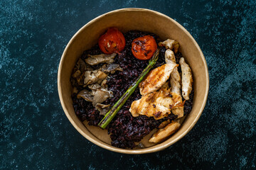 Healthy Food Bowl with Chicken, Black Rice or Wild Rice, Asparagus Mushroom, Avocado Mash and Roasted Grilled Tomatoes in Plastic Take Away Bowl