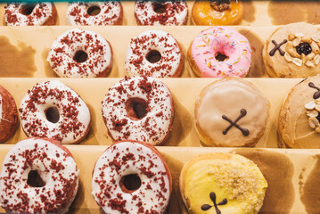 Assorted tasty colorful donuts on display, close up view. Street food market