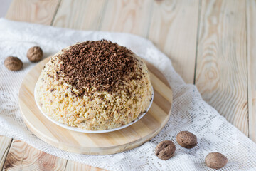 Traditional Russian anthill cake decorated with chocolate on light wooden background. Selective focus, horisontal