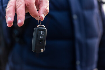 Man hand holding a car key. New car sell, auto showroom, car sale deal concepts. Black car key.