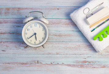 a white alarm clock on a light background. White, terry towel with buff, scissors and pusher for...