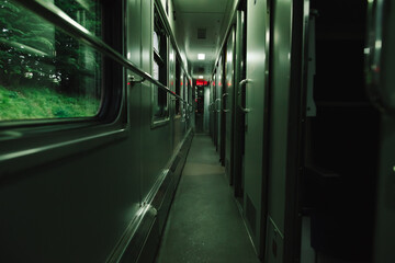 Obraz premium Interior of a train corridor. Evening photo of a compartment train. Empty train car on the road. Railway concept.