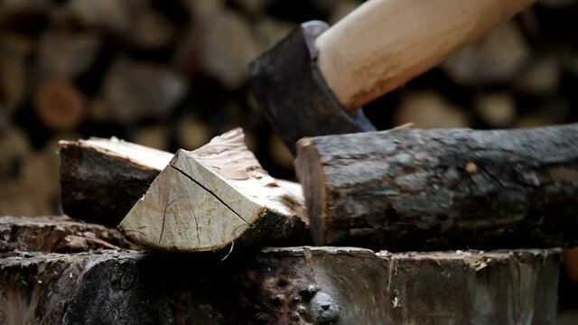 Splitting firewood with an axe. Cutting logs, harvesting firewood for the winter