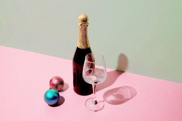 Artistic setup, champagne and Christmas balls on a pastel background in trendy colors.