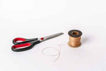 A spool of thread and scissors on a white background