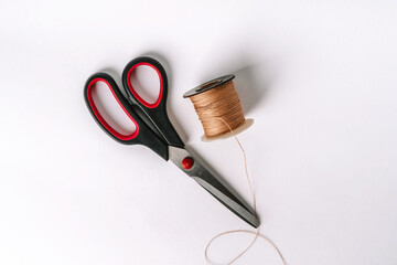 A spool of thread and scissors on a white background