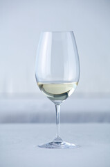 Ein Glas Weißwein auf einem weiß gedeckten  Tisch