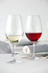 Ein Glas Rotwein und ein Glas Weißwein auf einem weiß gedeckten  Tisch