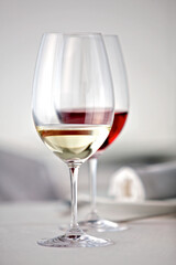 Ein Glas Rotwein und ein Glas Weißwein auf einem weiß gedeckten  Tisch