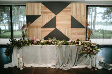 Vintage wedding decor. Beautiful event venue. Creative decoration. Hall decoration. Festive table decor. Stylish stone tablet with table number in grey, green branches and peonies, candles in gold can