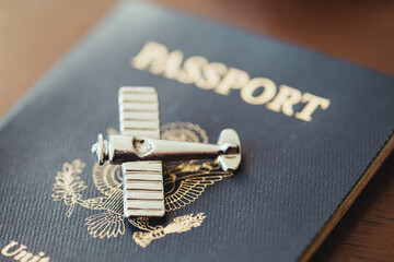 A silver antique airplane sitting on top of a blue American passport