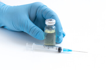 Doctor's Hand in blue gloves hold the vial with vaccine or drug on white background.